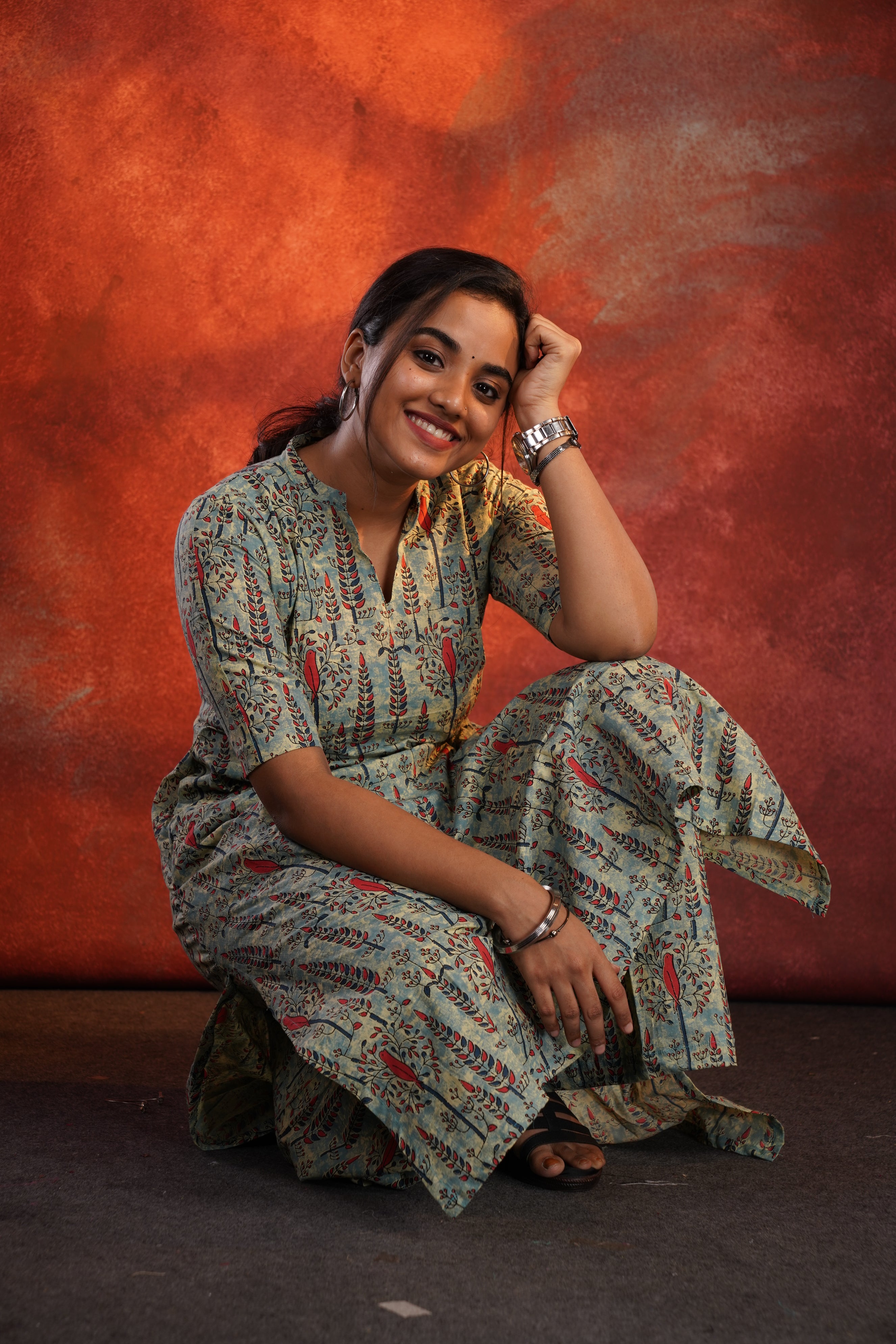 Woman in a patterned outfit lying on a red surface